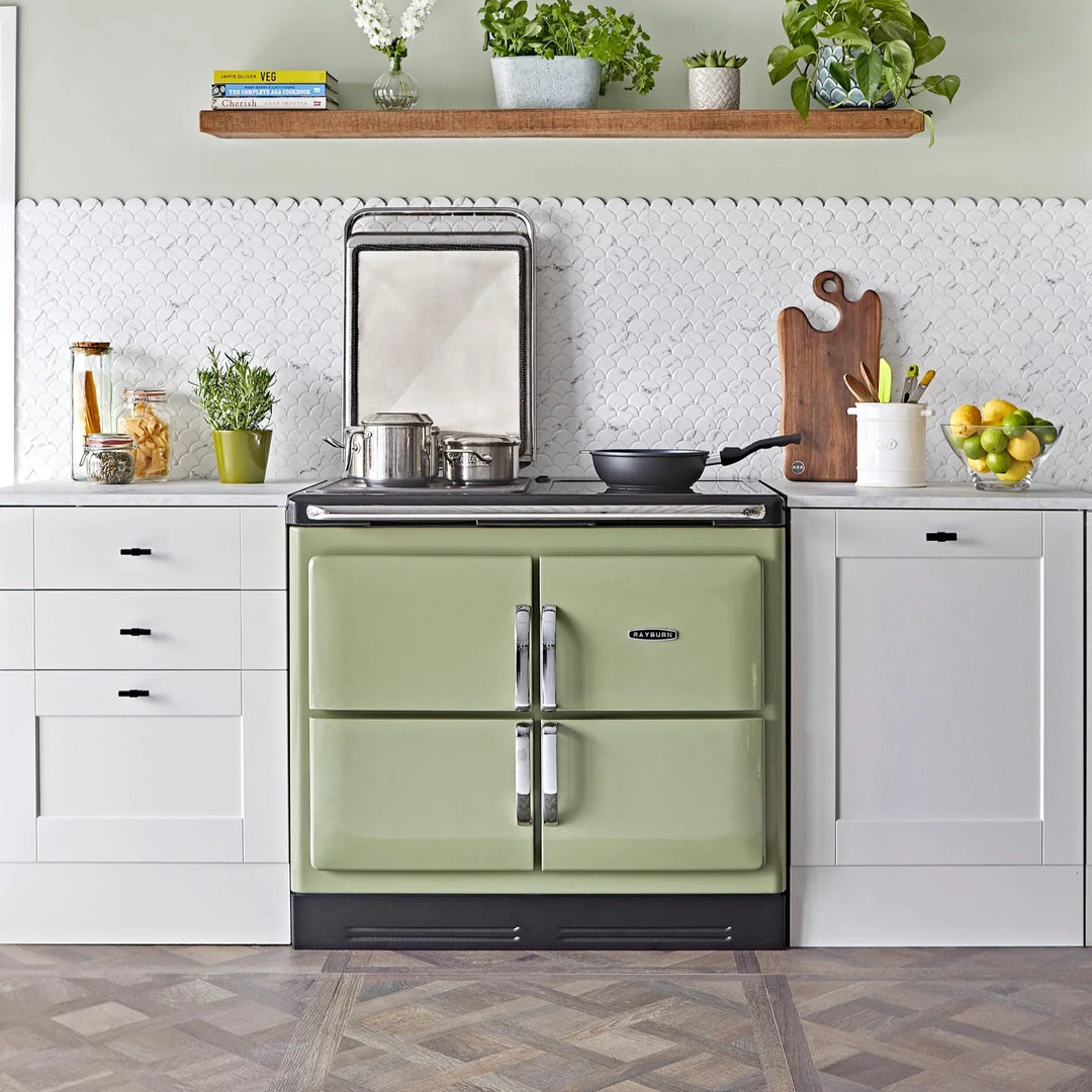 Rayburn range cooker in green within a white styled kitchen with pans on the hob