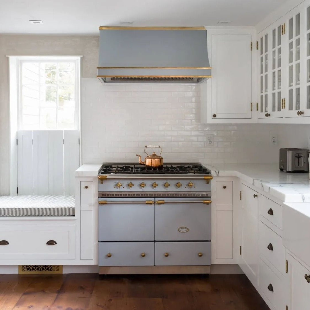 lacanche light blue and gold trim cooker in a white kitchen with matching hood
