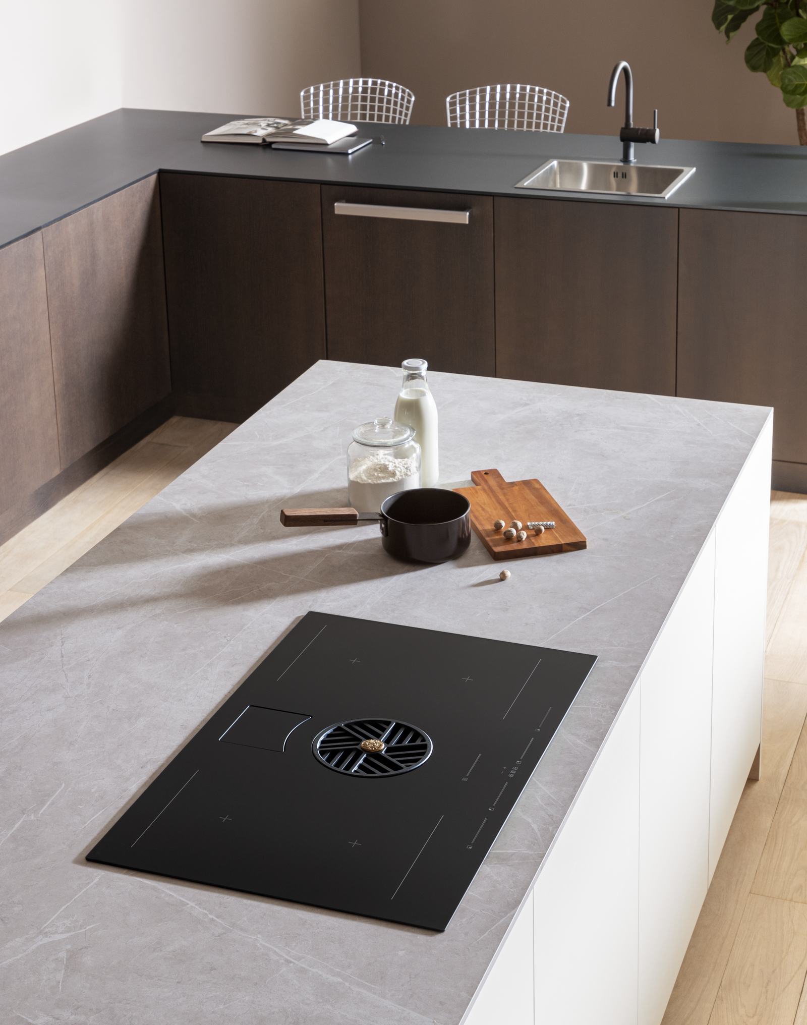 Bertazzoni hob with ventilation in a stylish kitchen with white marble counter contrasting against black induction hob