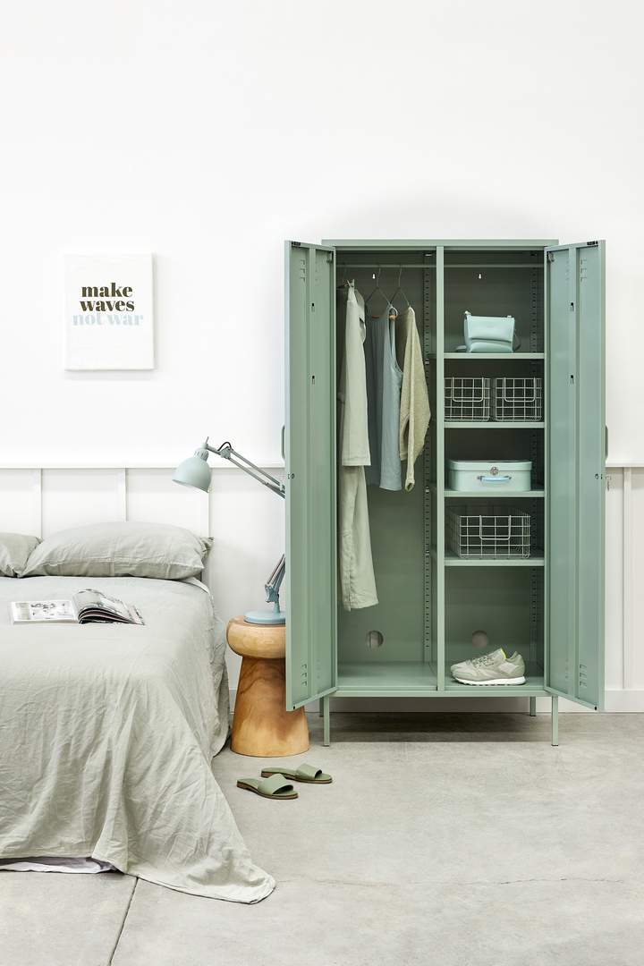 Mustard Made The Twinny Locker in sage with the door open and clothes inside beside a bed