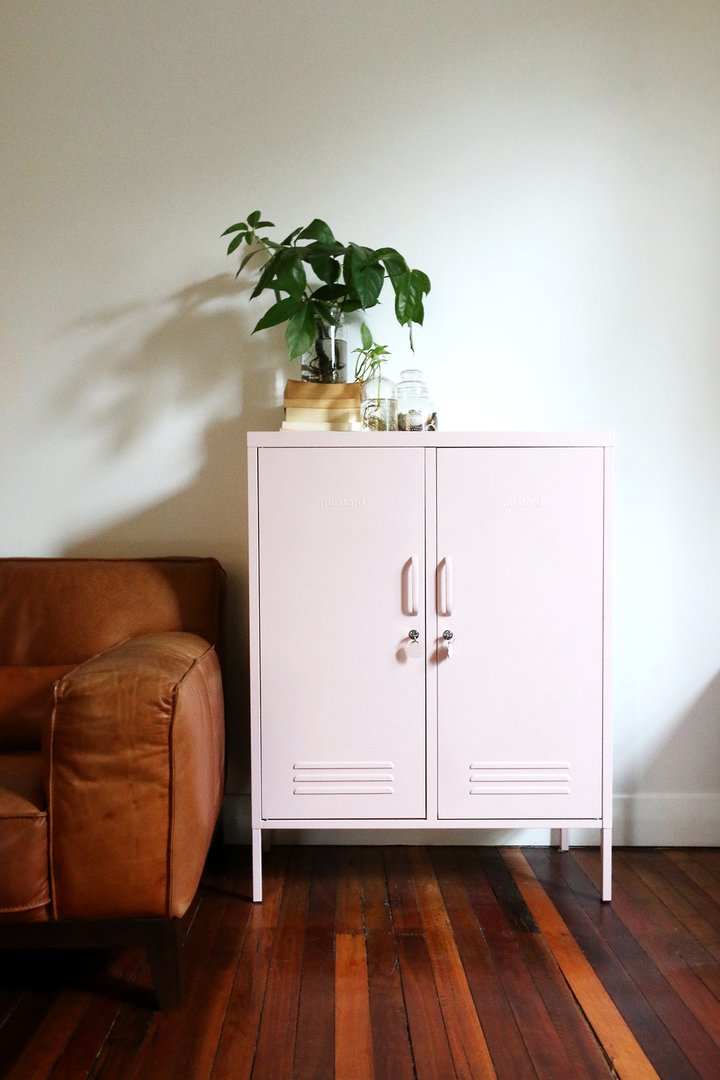 Mustard Made The Midi Locker in blush beside a leather couch with a plant on top