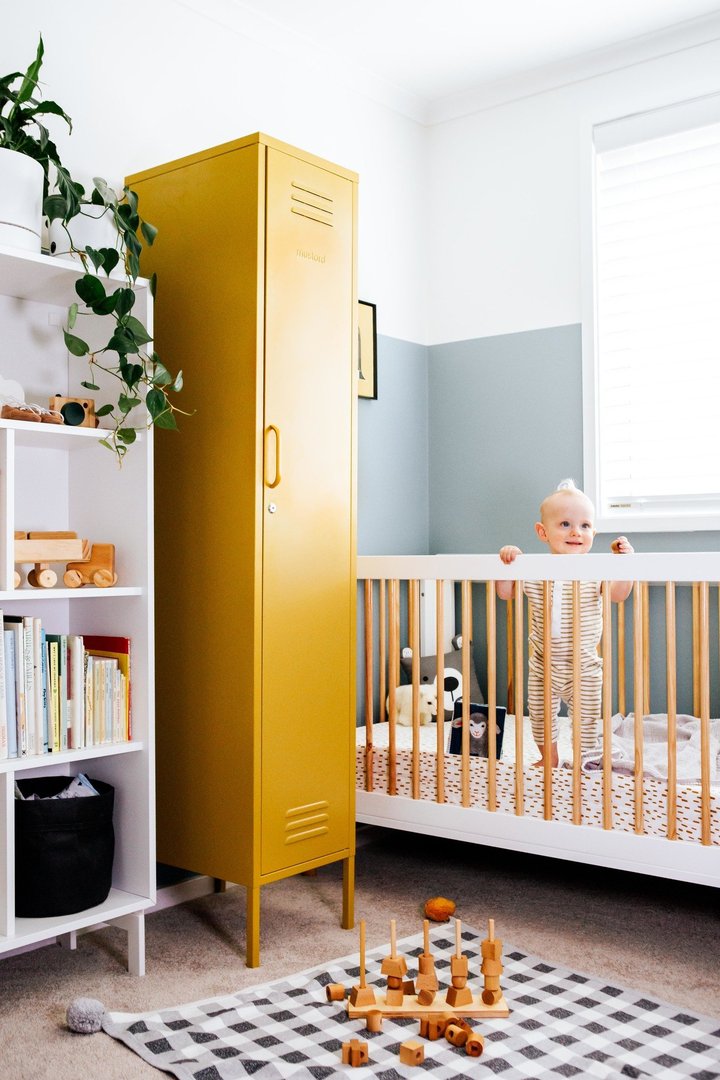 Mustard Made The Skinny Locker in mustard beside a baby that is in its cot